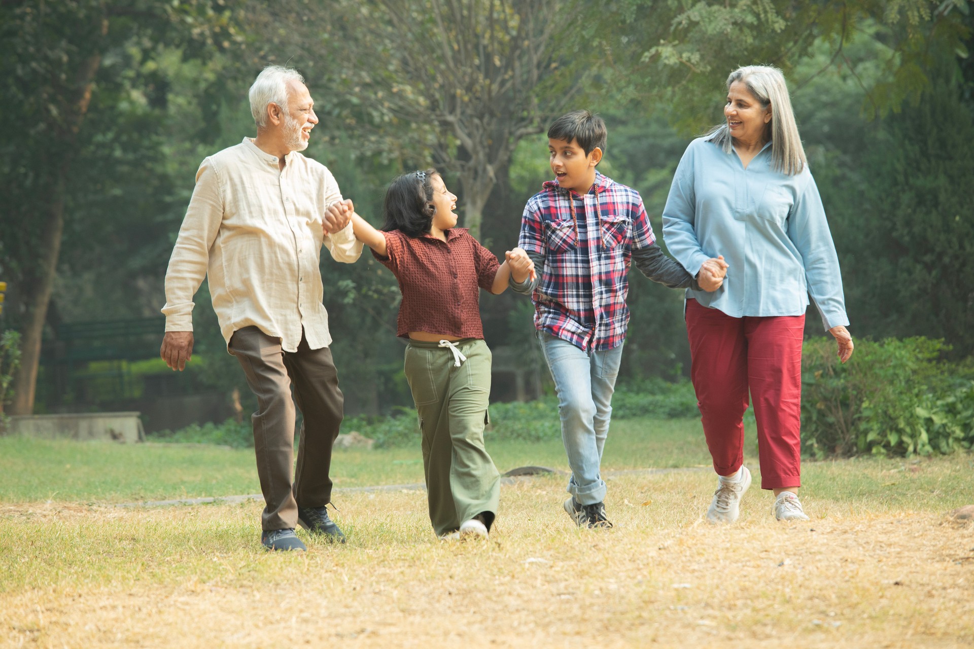 Happy grandparents holding children's hands in park